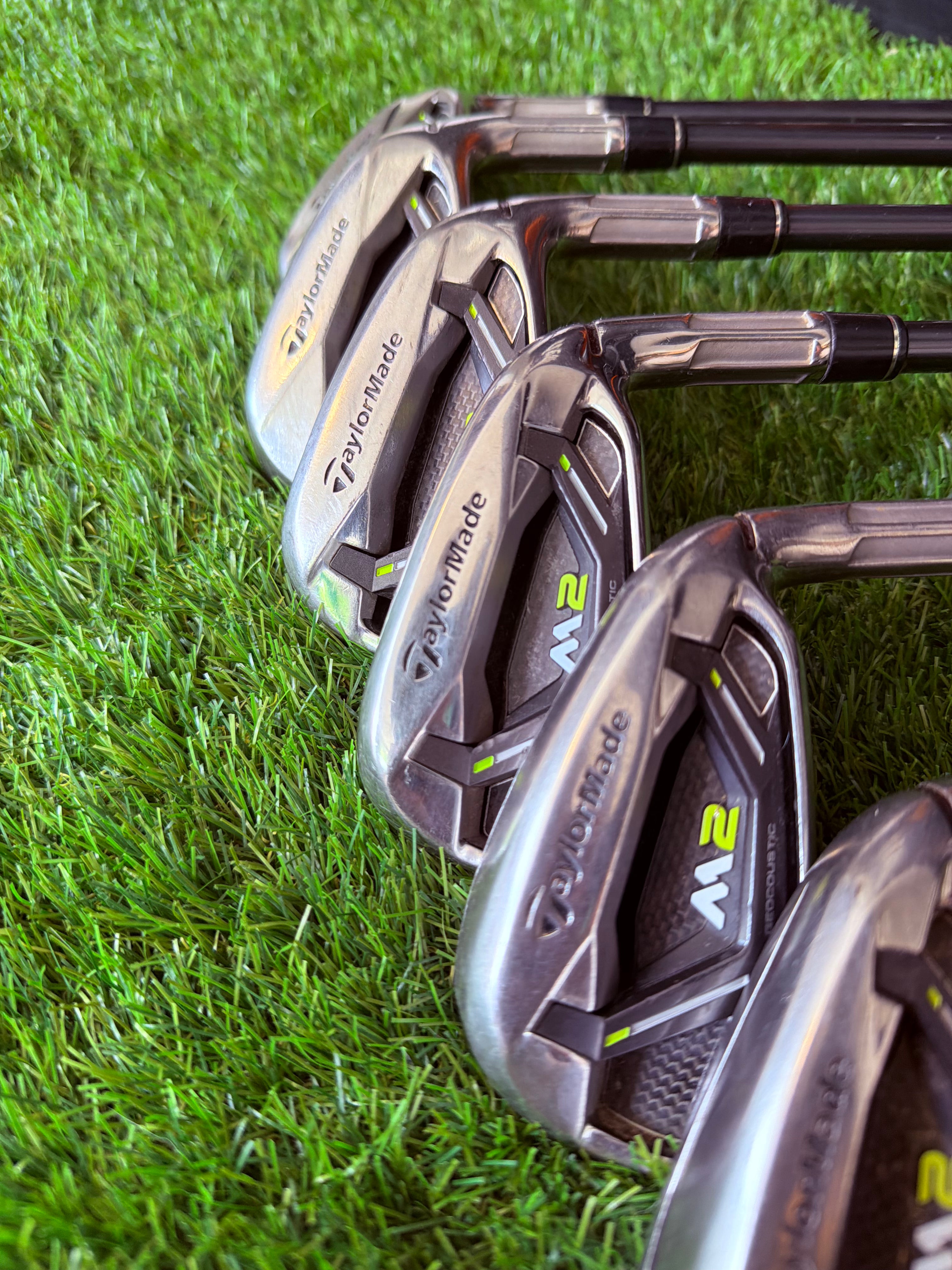 Rechtshandige TaylorMade M2 ijzers 5 tot PW met graphite shaft op een golfbaan, klaar voor gebruik.