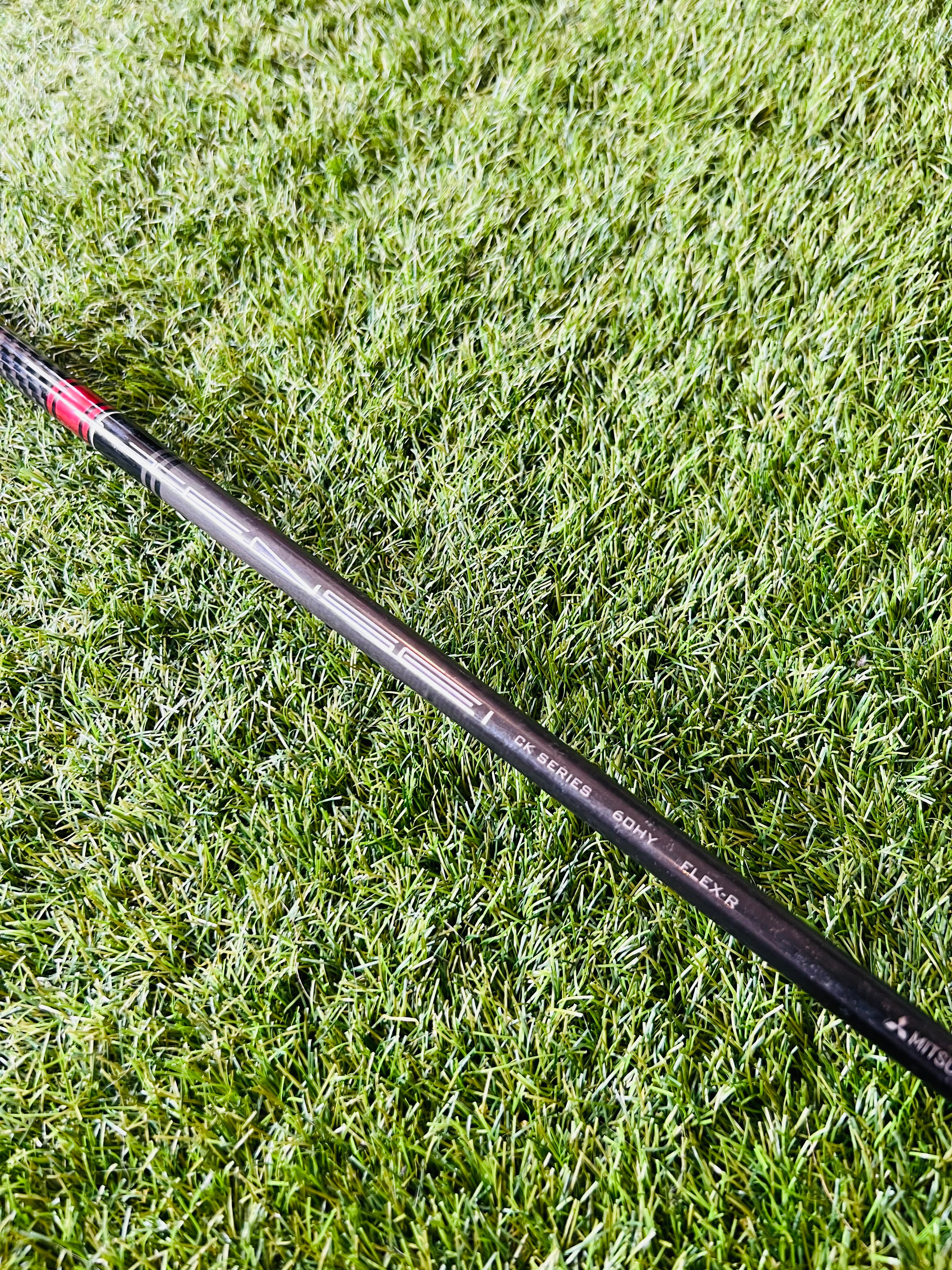 Titelist 818 H1 hybride 23° rechtshandig, golfclub met graphite shaft en zwarte grip, liggend op een greenset.