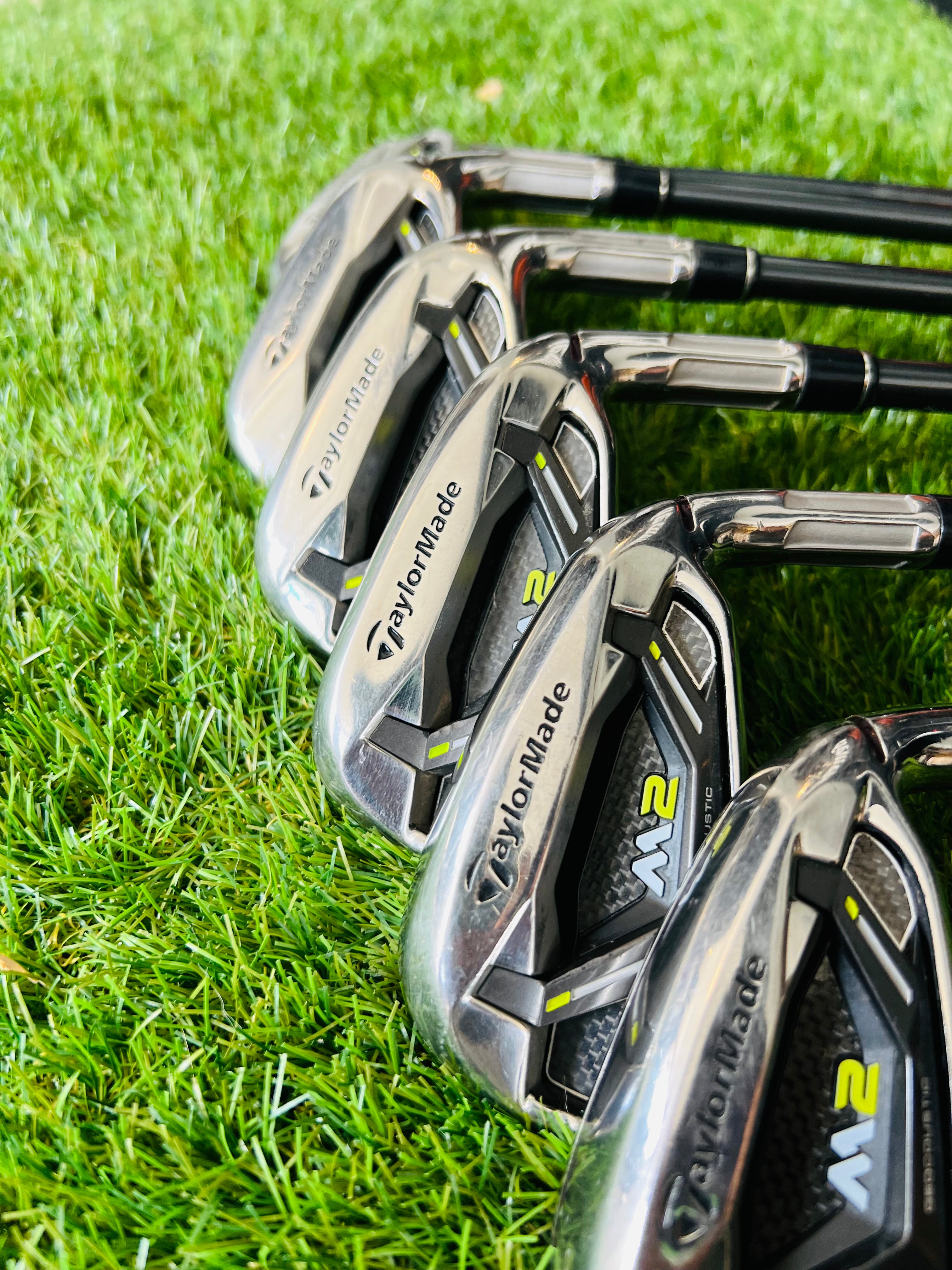 TaylorMade M2 ijzerset 5 tot PW rechtshandig met +0,5 graads lie, golfclubs liggend op een houten vloer