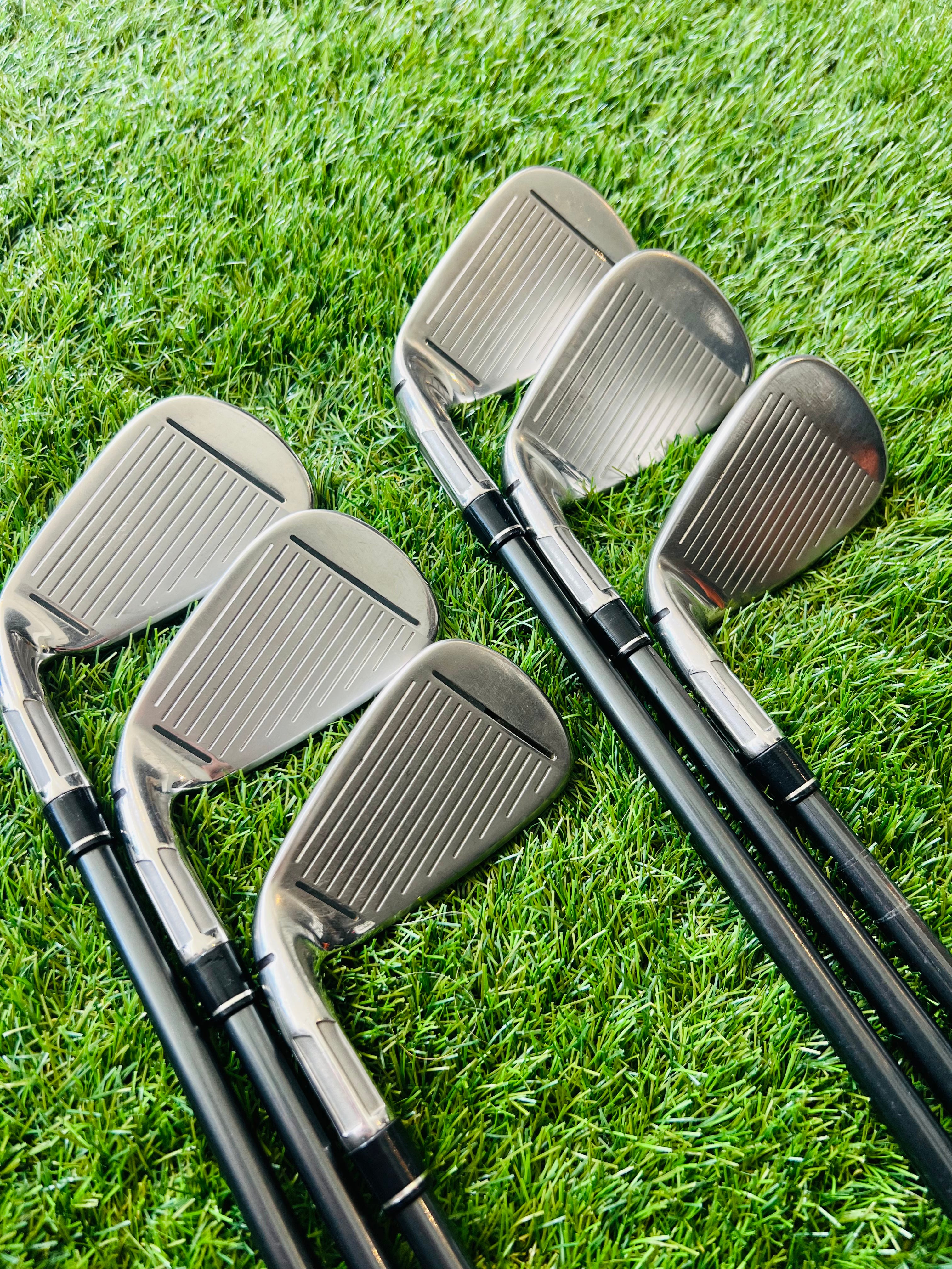 TaylorMade M2 ijzerset 5 tot PW voor rechts, inclusief +0,5 lie angle, liggend op een golfbaan met clubs en golfballen