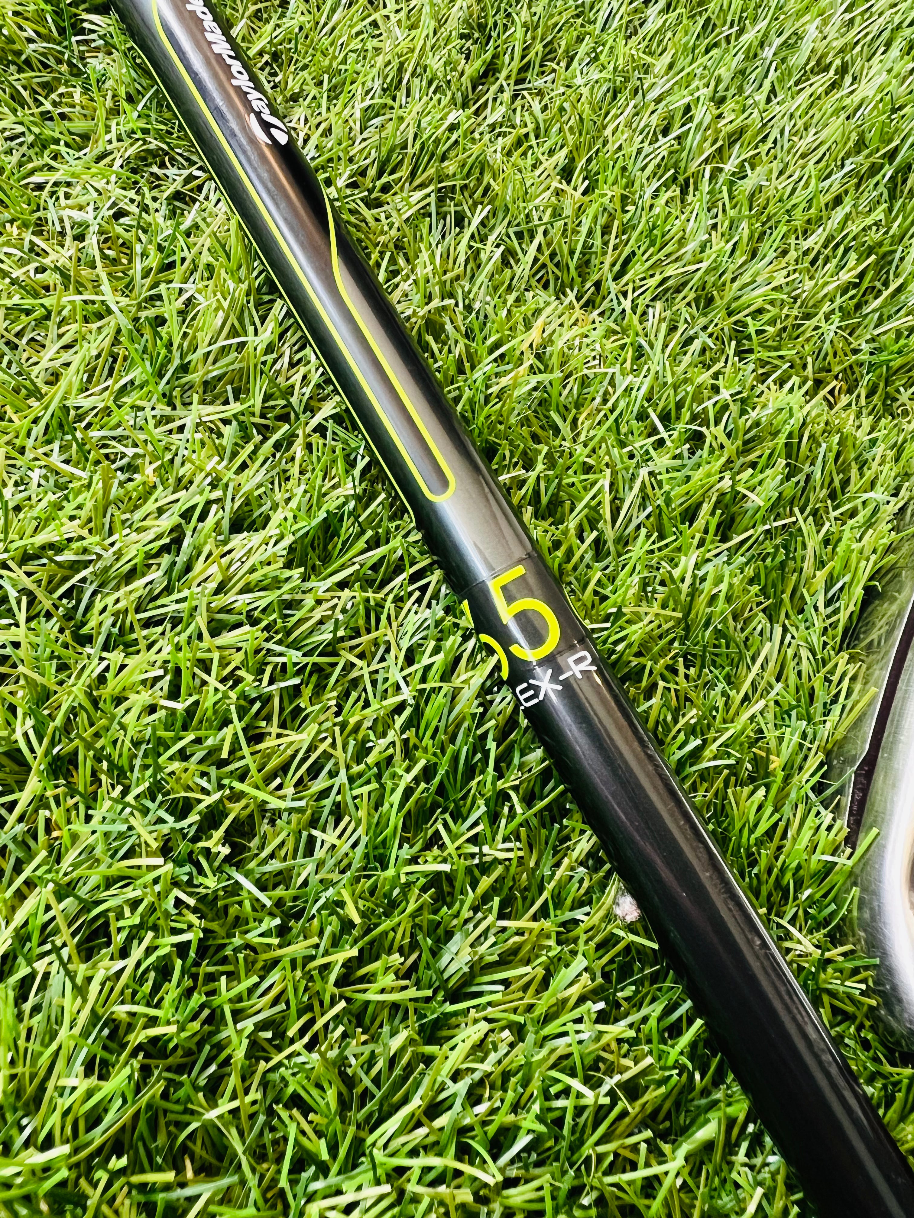 Rechtshandig TaylorMade M2 ijzerset 5 t/m PW met +0,5 flex, liggende clubs op een golfbaan met golfballen en tas