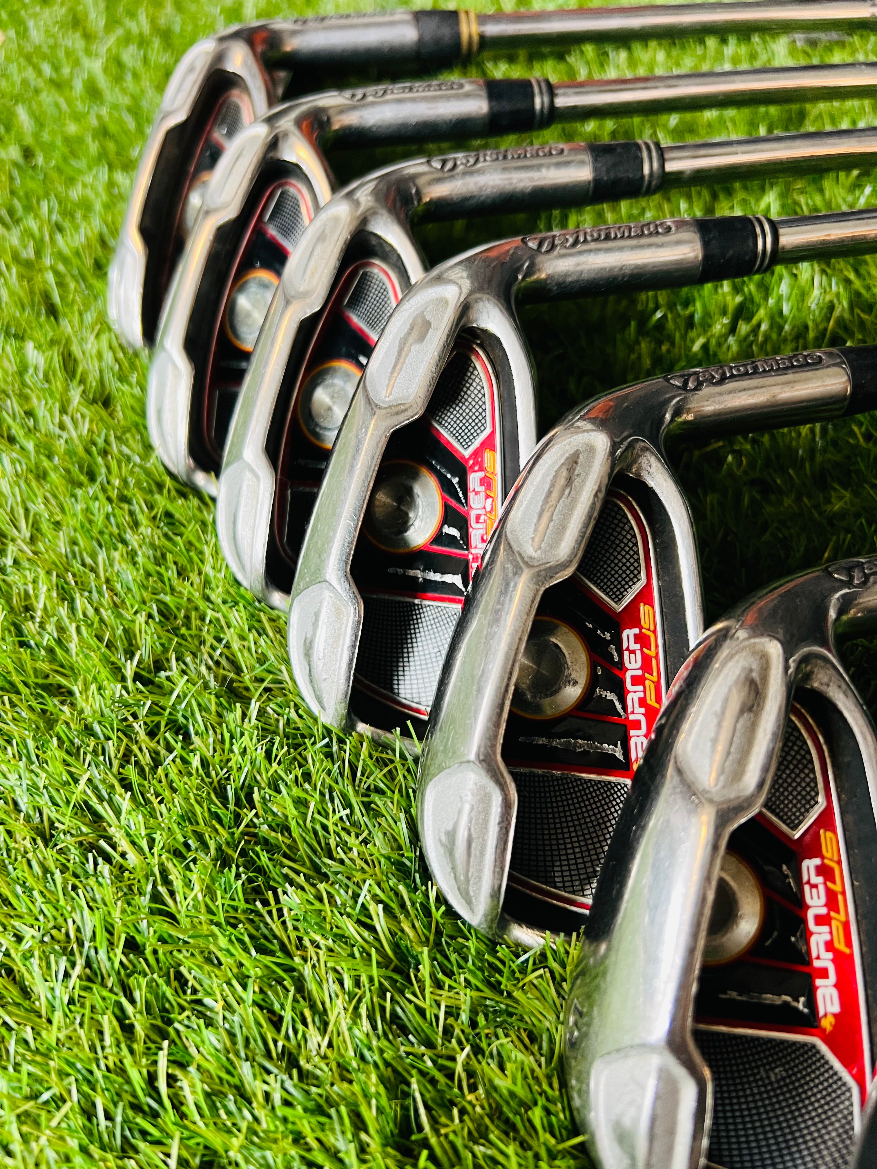 TaylorMade Burner Plus ijzers 4 tot PW rechtshandig met +0,5 graad lie, liggend op golfbaan, clubs voor golfspel.