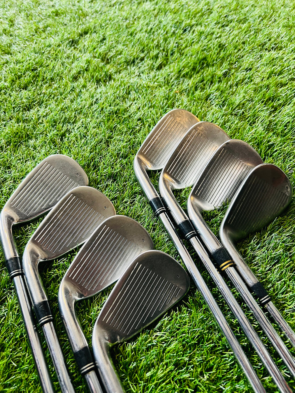 Rechtshandige TaylorMade Burner Plus ijzers 4 tot PW met +0,5 lie, liggende set op golfbaan met clubs en tas