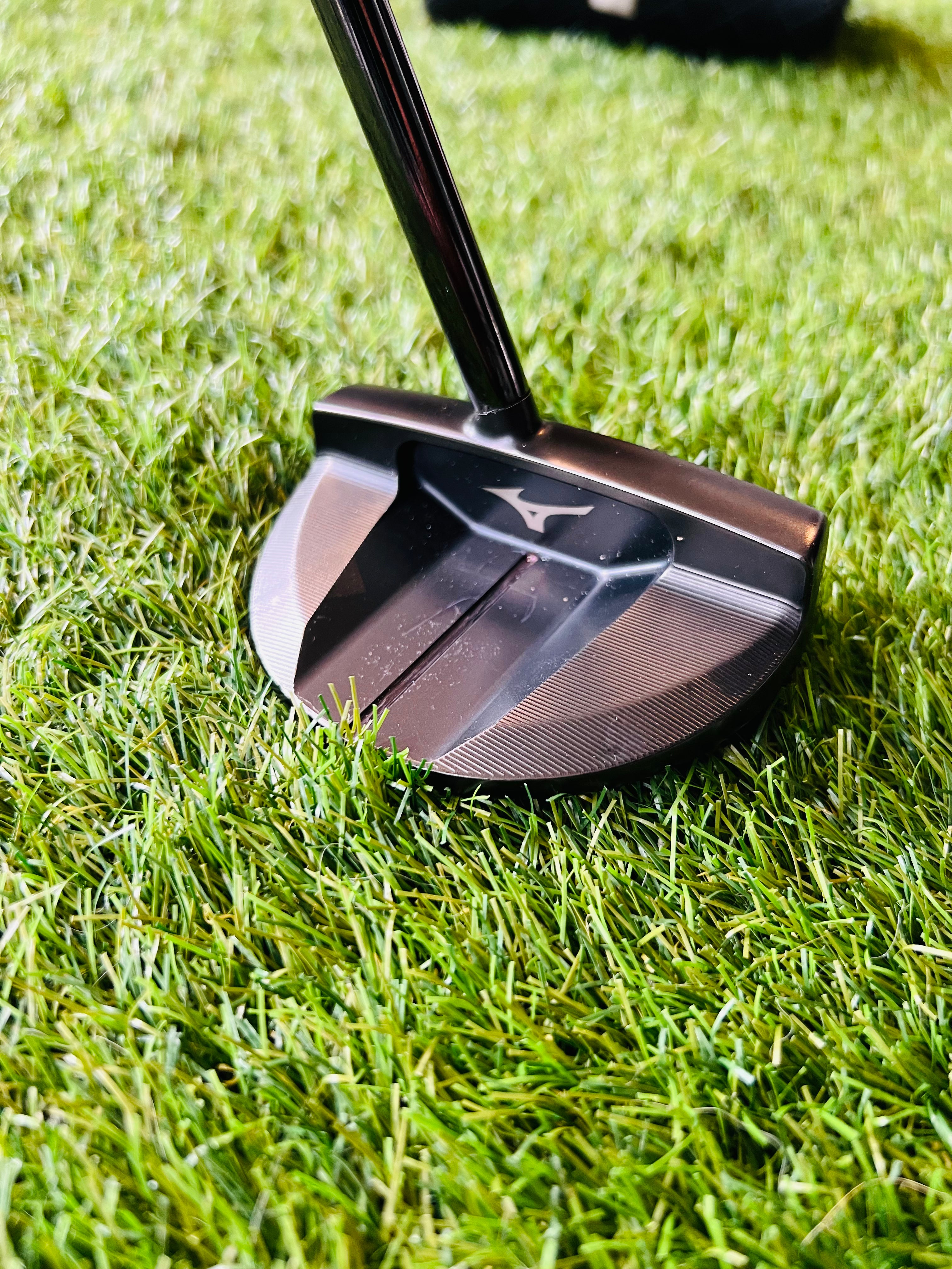 Rechtshandige Mizuno M-Craft OMOI 05 putter van 34 inch, liggend op een golfbaan, met houten handvat en zilveren kop.