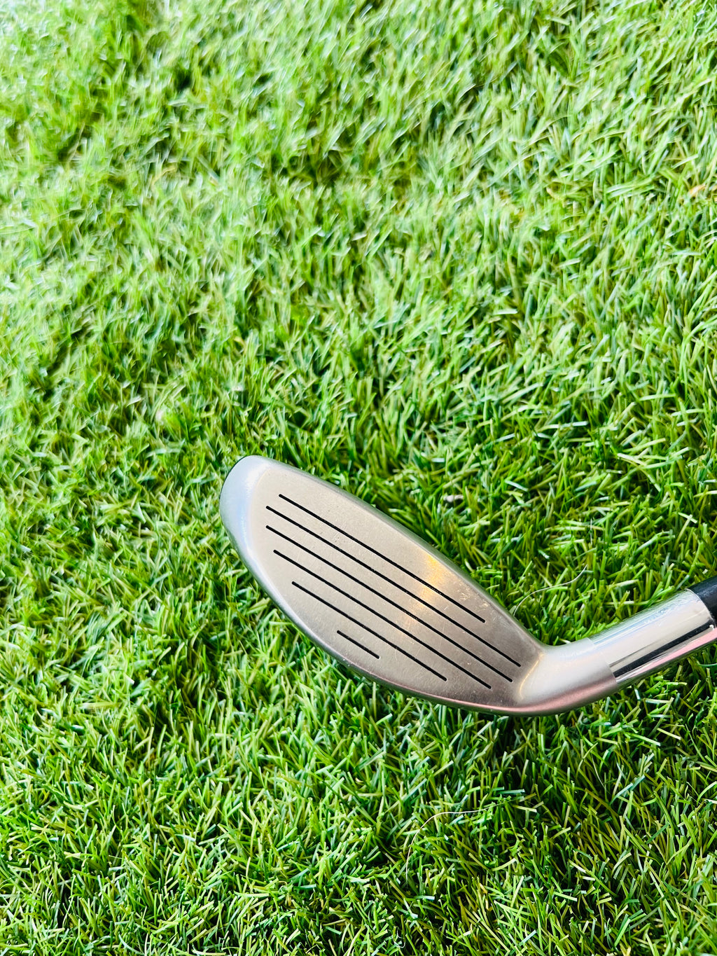 Rechtshandige Callaway RAZR X Tour hybride 2 (18°) golfclub met blauwe en zwarte afwerking, gelegen op een golfbaan.