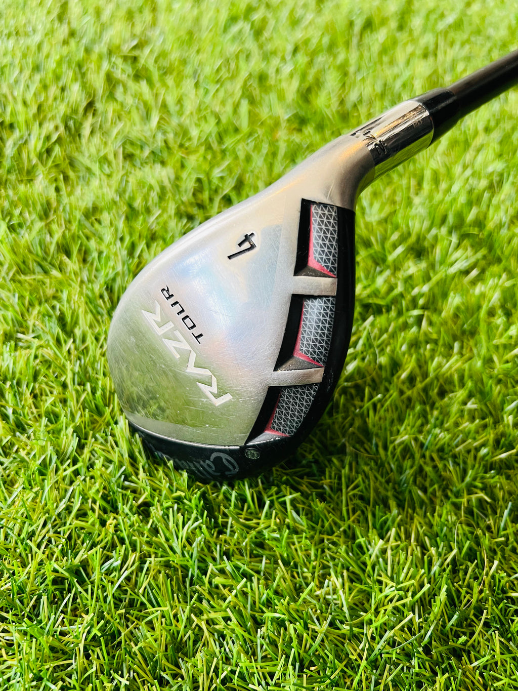 Rechtshandige Callaway RAZR X Tour hybride 4 (24°) met houten afwerking en grafiet shaft, liggend op een golfbaan.