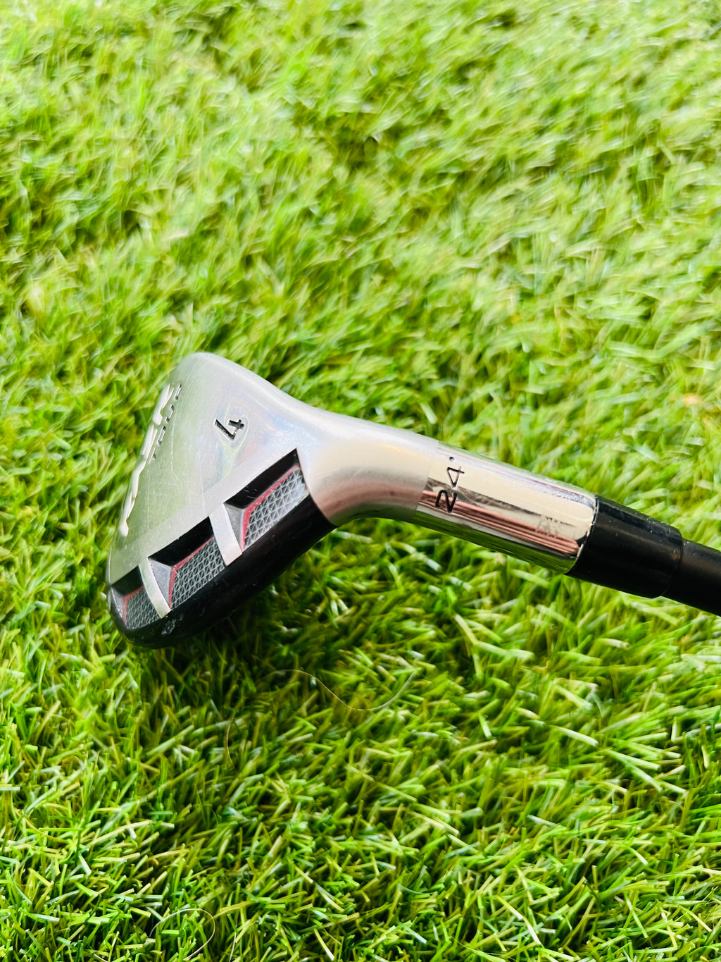 Rechtshandige Callaway RAZR X Tour hybride 4 met 24° loft, golfclub met zwarte grip en clubhoofd op golfbaan.