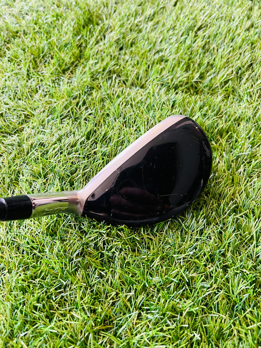 Rechtshandige Callaway RAZR X Tour hybride 4 (24°) golfclub met metalen kop en grip, liggend op groene golfbaan.