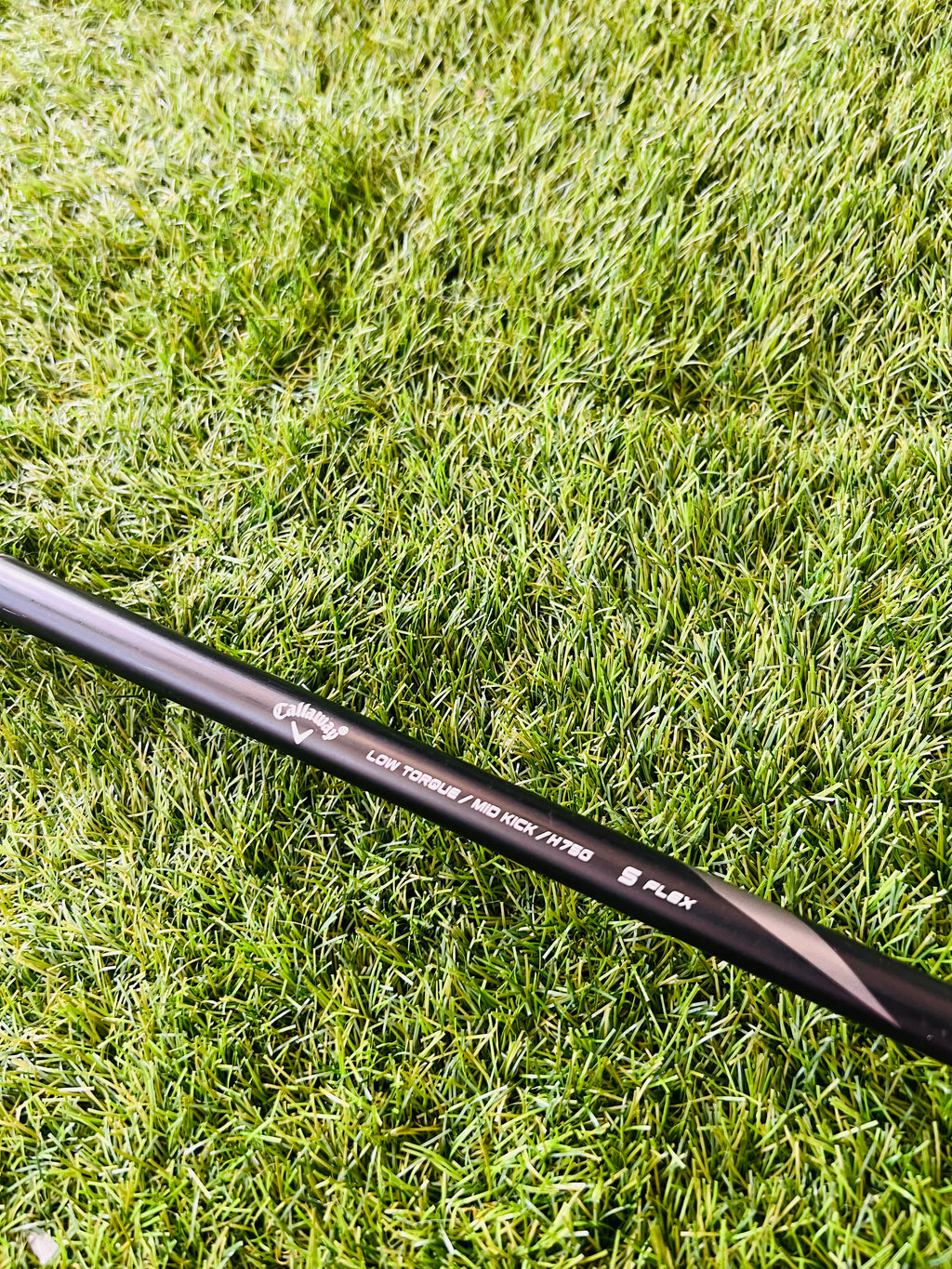 Rechtshandige Callaway RAZR X Tour hybride 4 (24°) met graphite shaft, liggend op golfbaan, close-up van clubkop.