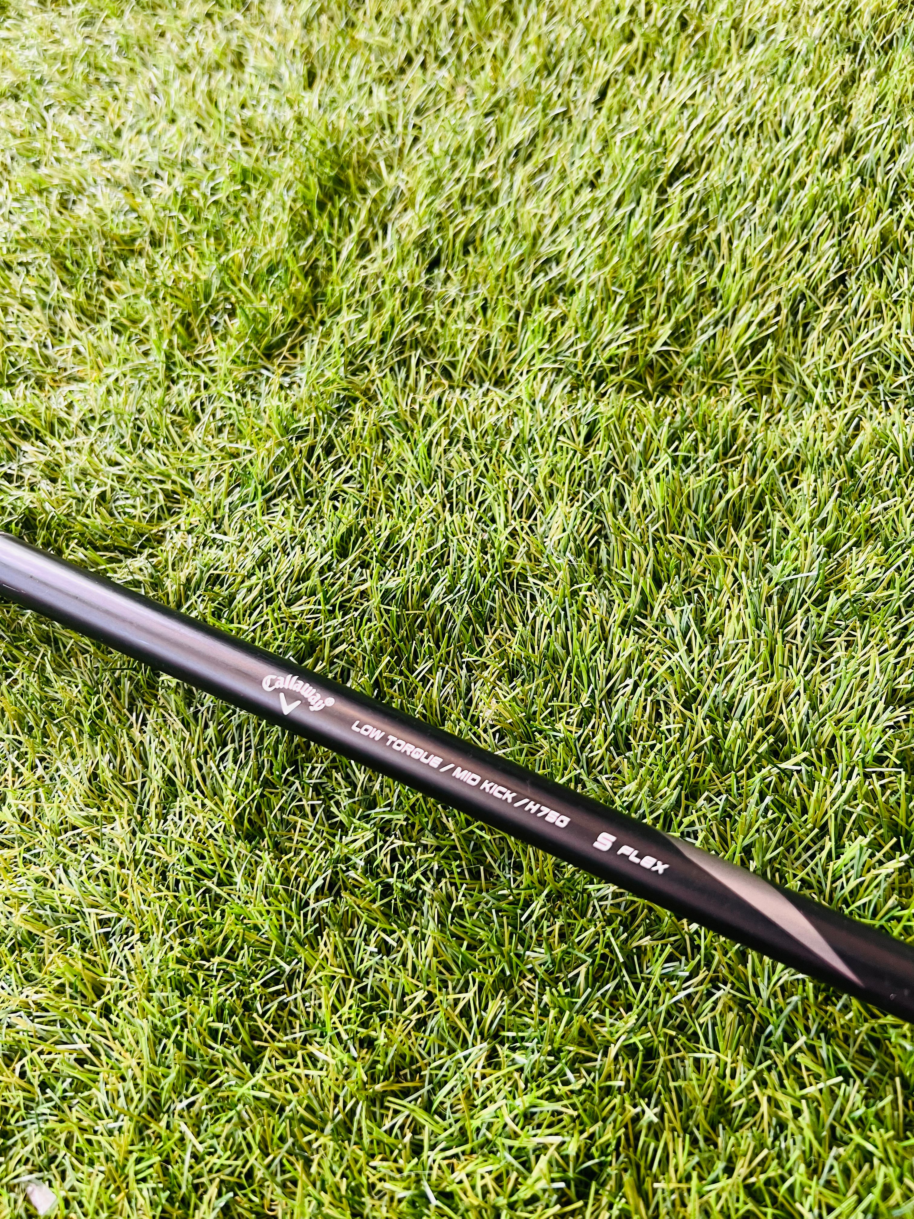 Rechtshandige Callaway RAZR X Tour hybride 4 (24°) met graphite shaft, liggend op golfbaan, close-up van clubkop.