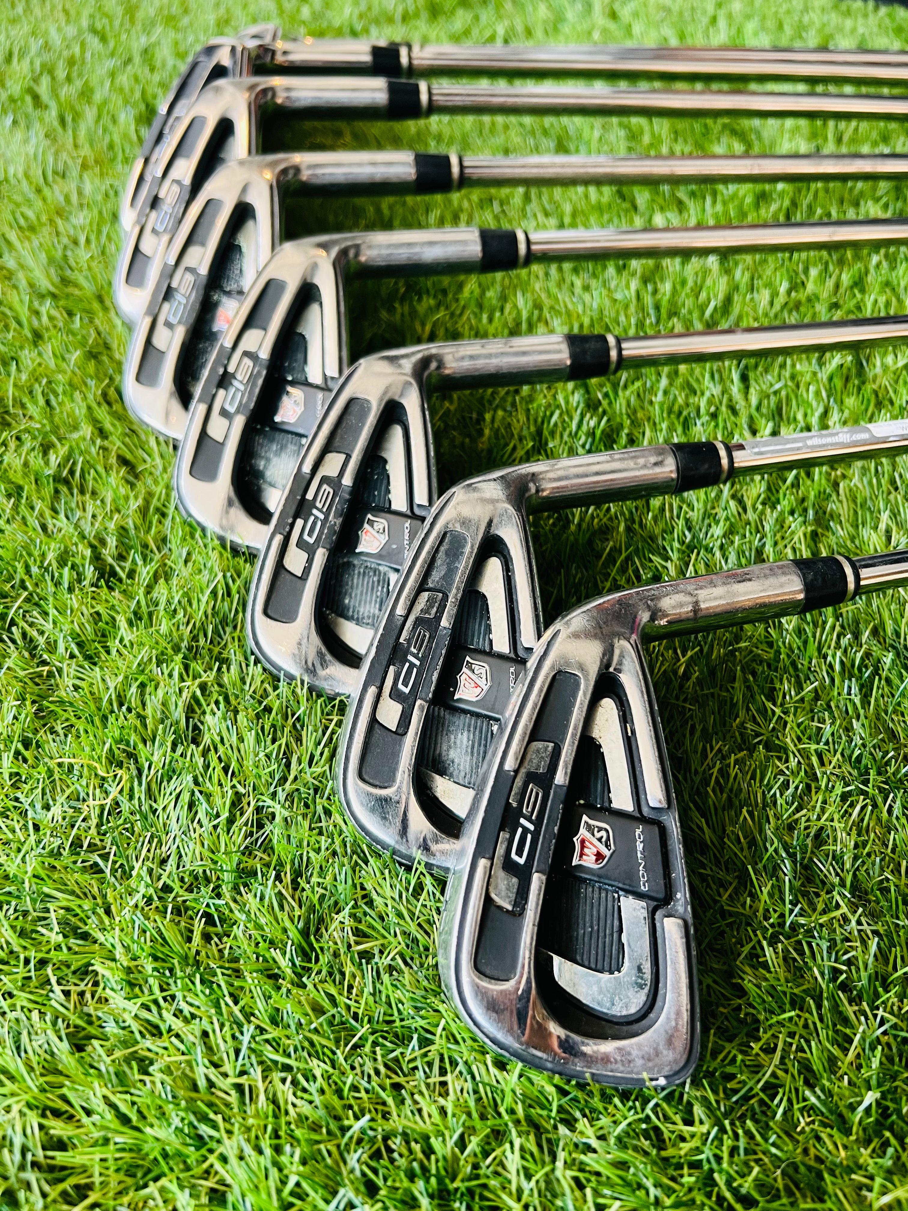 Rechtshandige Wilson Staff Ci9 ijzerset 4 tot PW met golfwedge, ligt in golfclub met clubs zichtbaar.