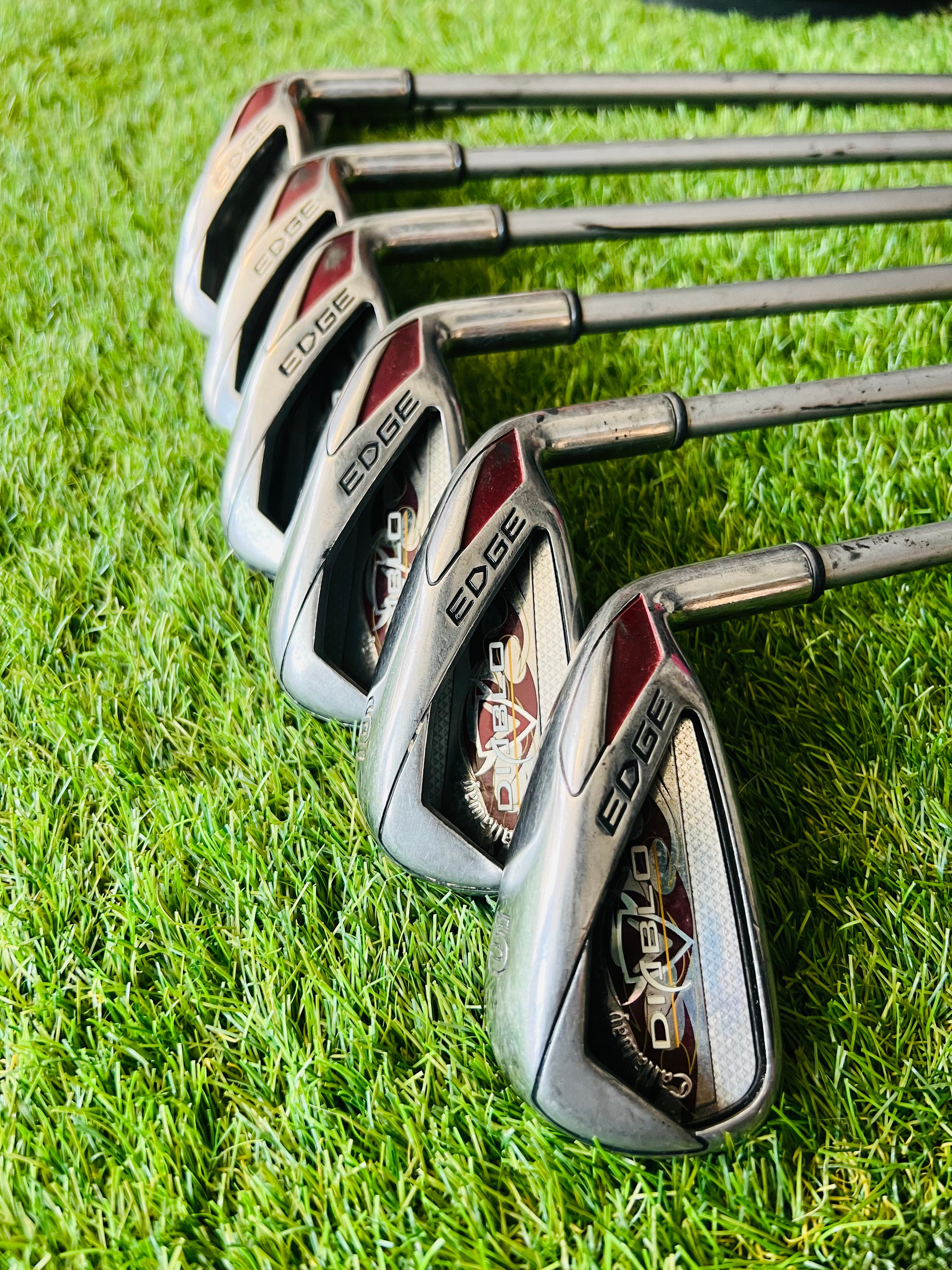 Callaway Diablo Edge dames ijzers 5 tot SW, golfclubs met blauwe en zilveren afwerking, liggend op een houten vloer