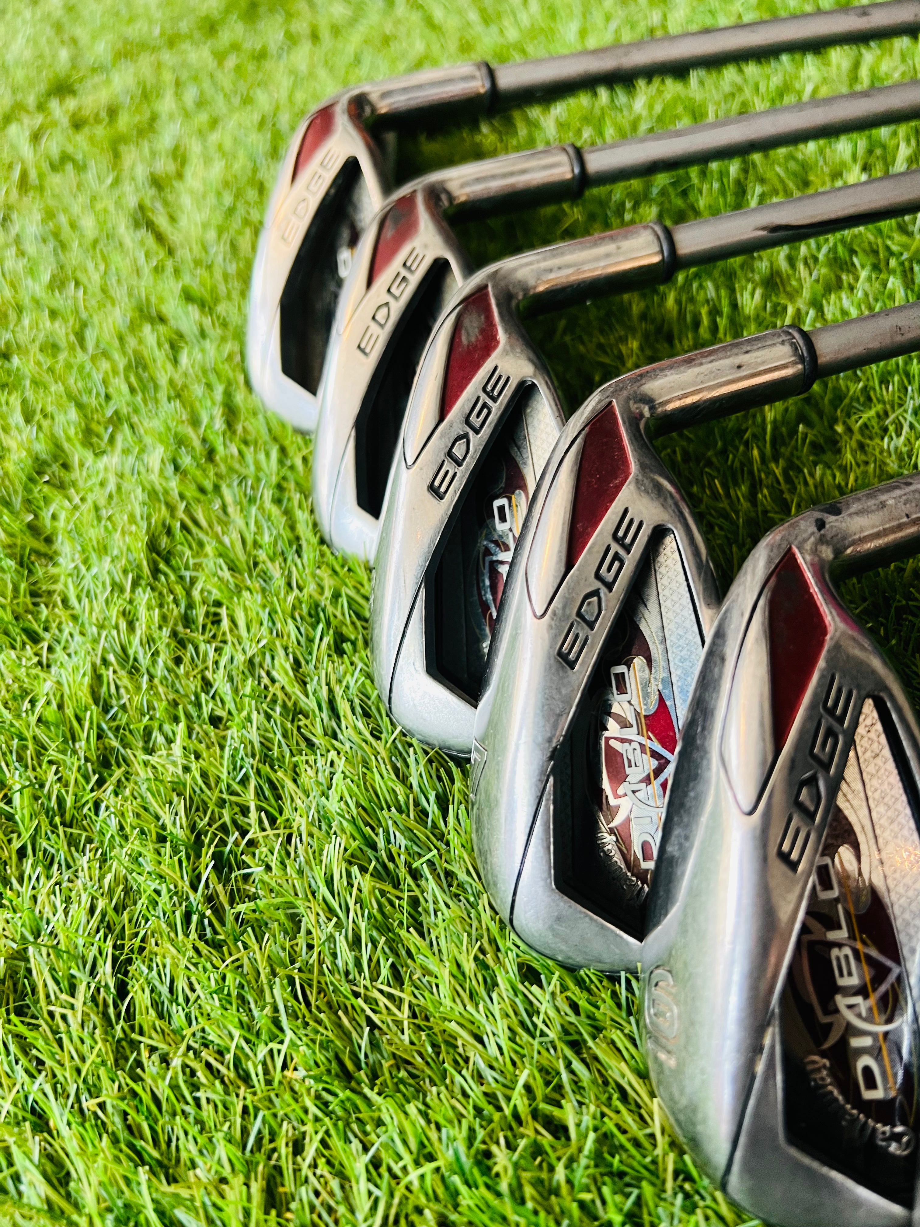 Vrouwelijke golfer met Callaway Diablo Edge dames ijzers, 5 tot SW, op de golfbaan, in actie met golfclubs in de hand