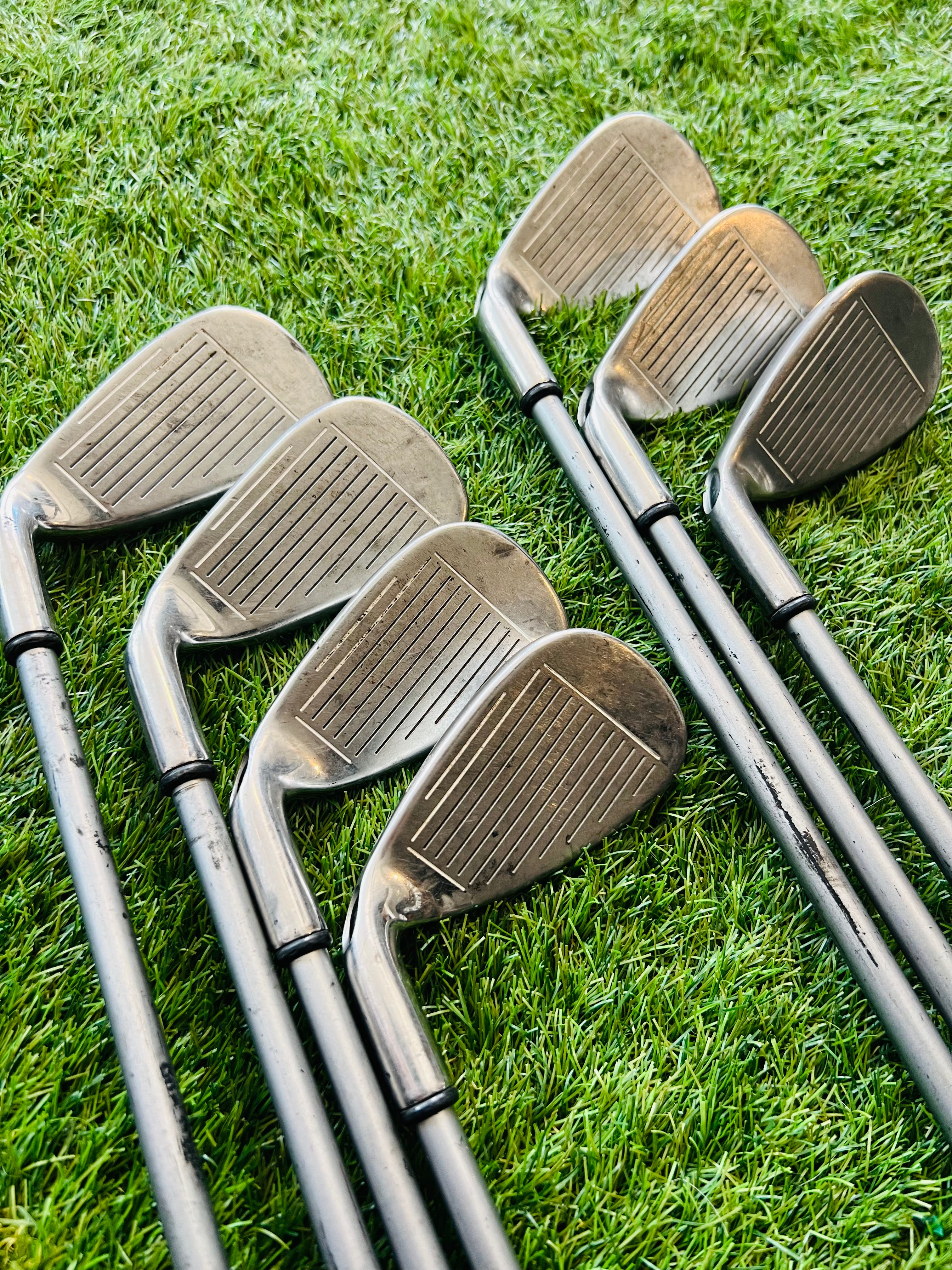 Callaway Diablo Edge dames ijzers 5 tot en met SW, golfclubs met zwarte grips en roestvrijstalen clubhoofden, op een golfbaan.