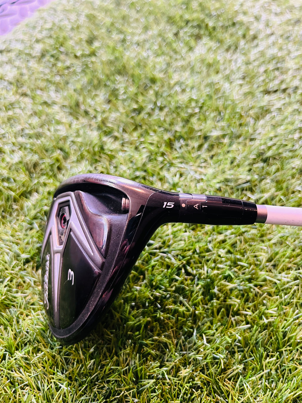 Titleist 915F fairwayhouten 5 (18°) voor rechts, met houten clubhoofd en grip, liggend op een golfbaan.