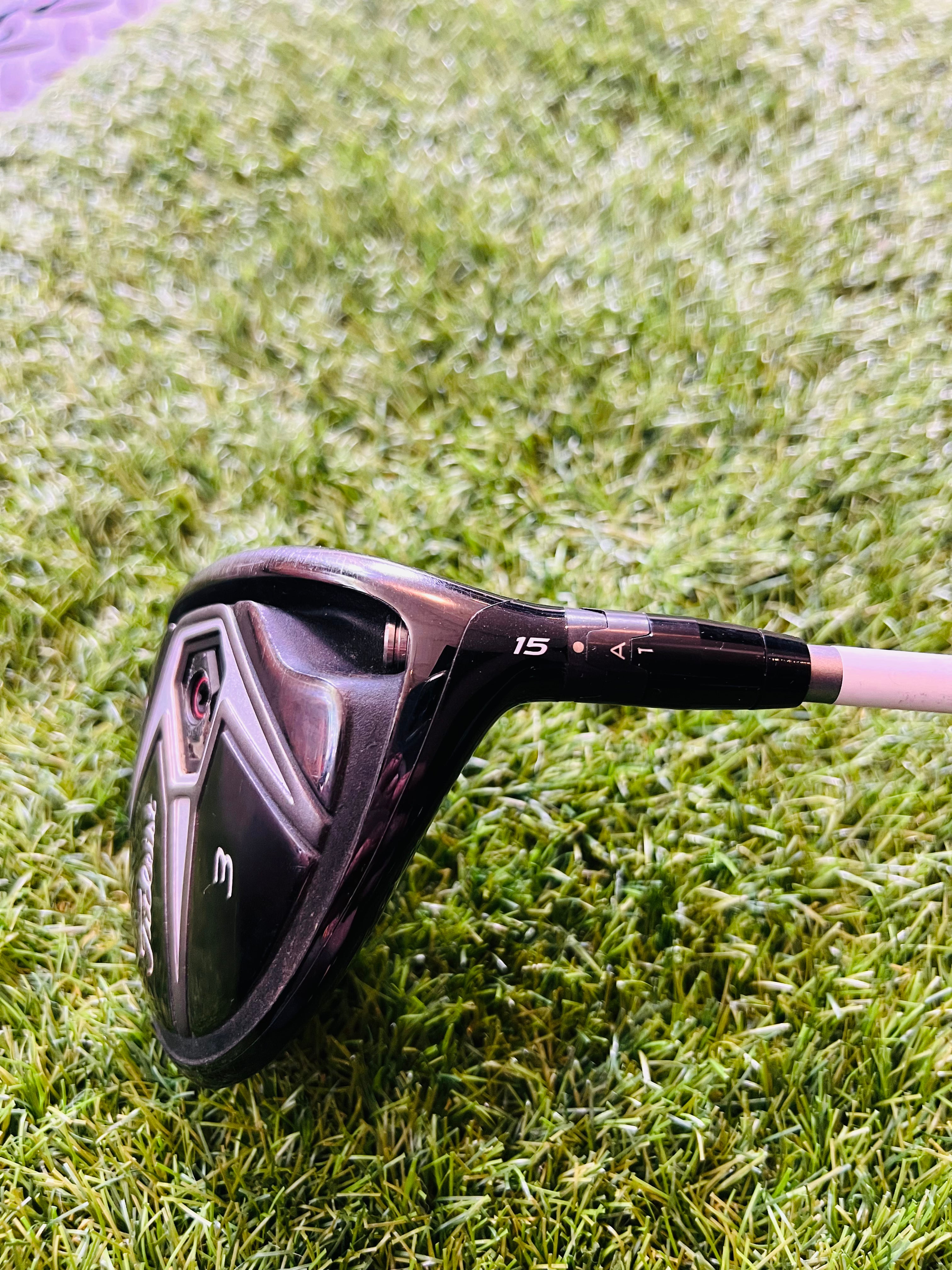 Titleist 915F fairwayhouten 5 (18°) voor rechts, met houten clubhoofd en grip, liggend op een golfbaan.