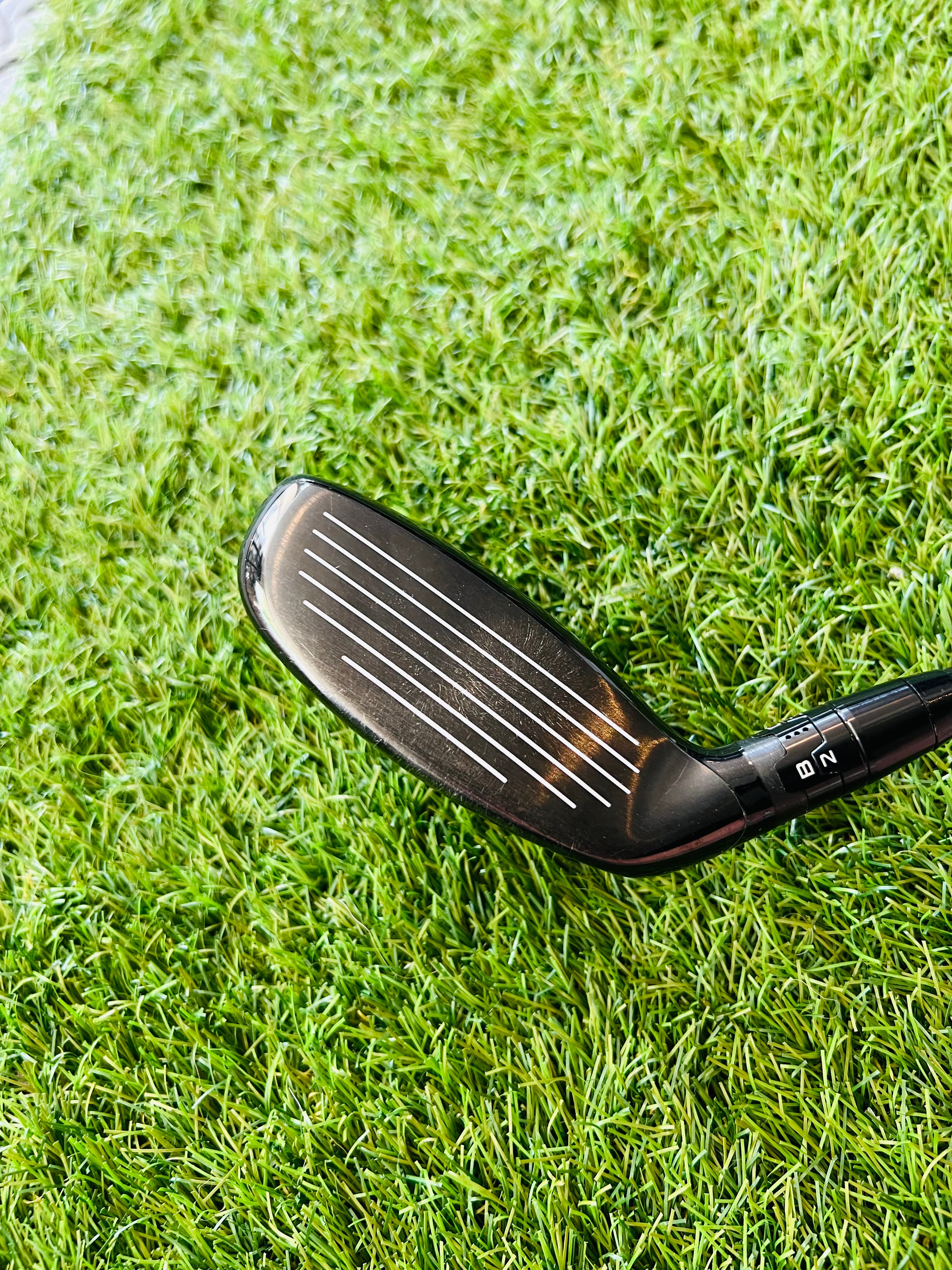 Titleist 915H hybride 2 met 18° loft, rechtshandig, golfclub met zwarte shaft en grip op een golfbaan