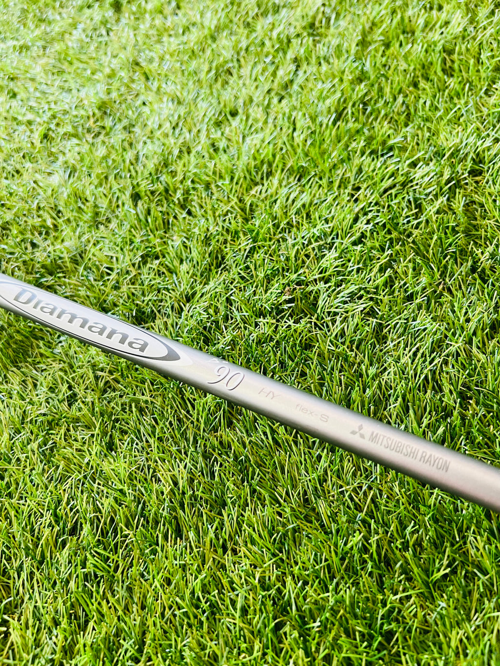 Titleist 915H hybride 2 met 17,5° loft, rechtshandig, gelegen op golfbaan met clubs en golfballen op de achtergrond