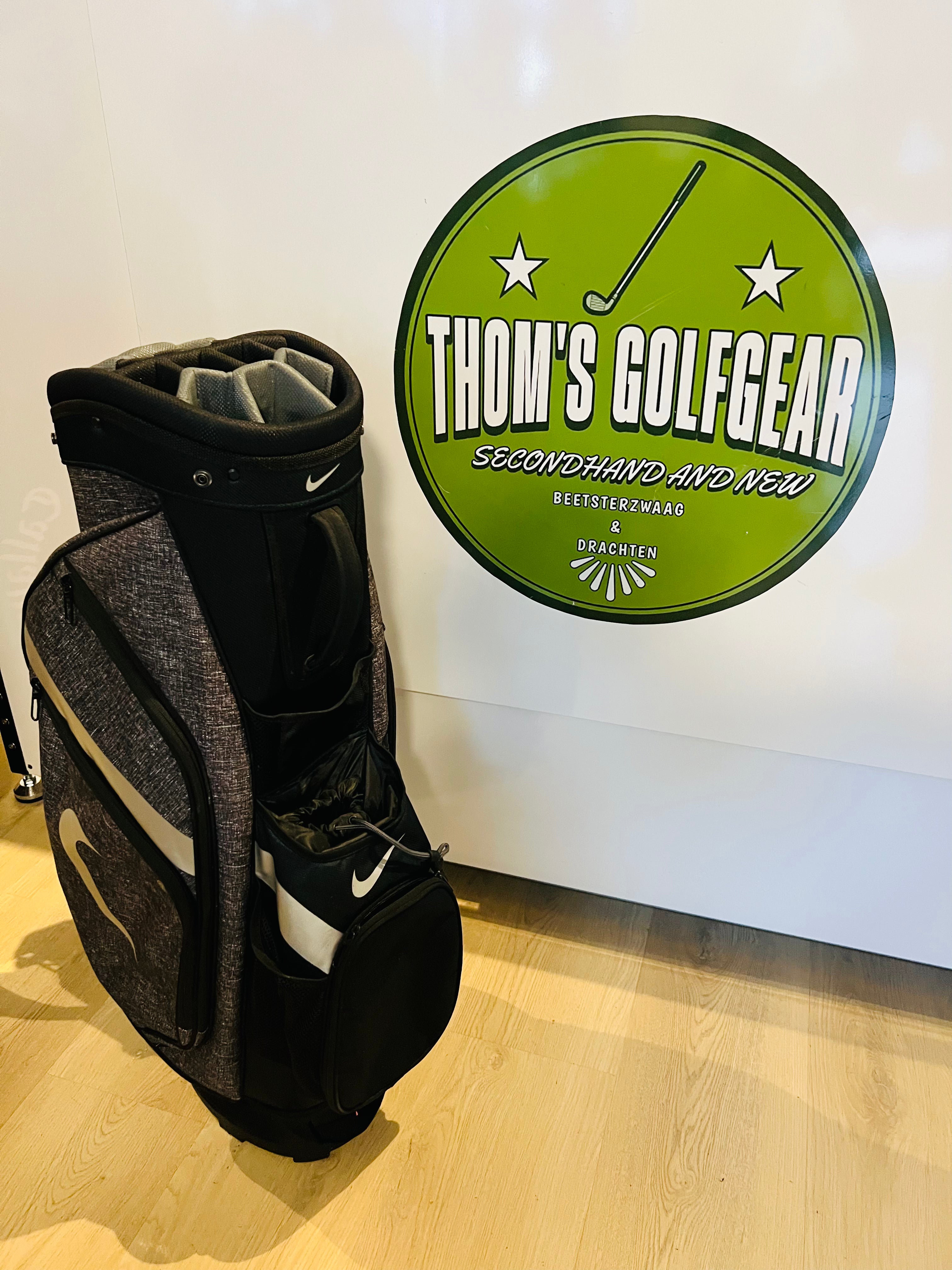 Zwarte en grijze Nike golfcartbag met 14 vakken en regencover, Thom's Golfgear golftas zichtbaar in de afbeelding.
