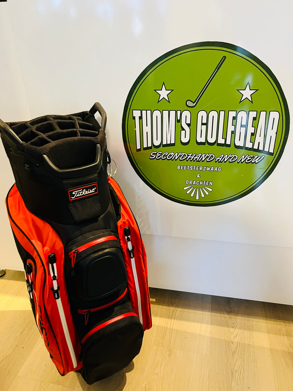 Rode en zwarte Titleist StaDry golfcarttas met meerdere vakken en handvatten, geschikt voor golfclubs en accessoires.