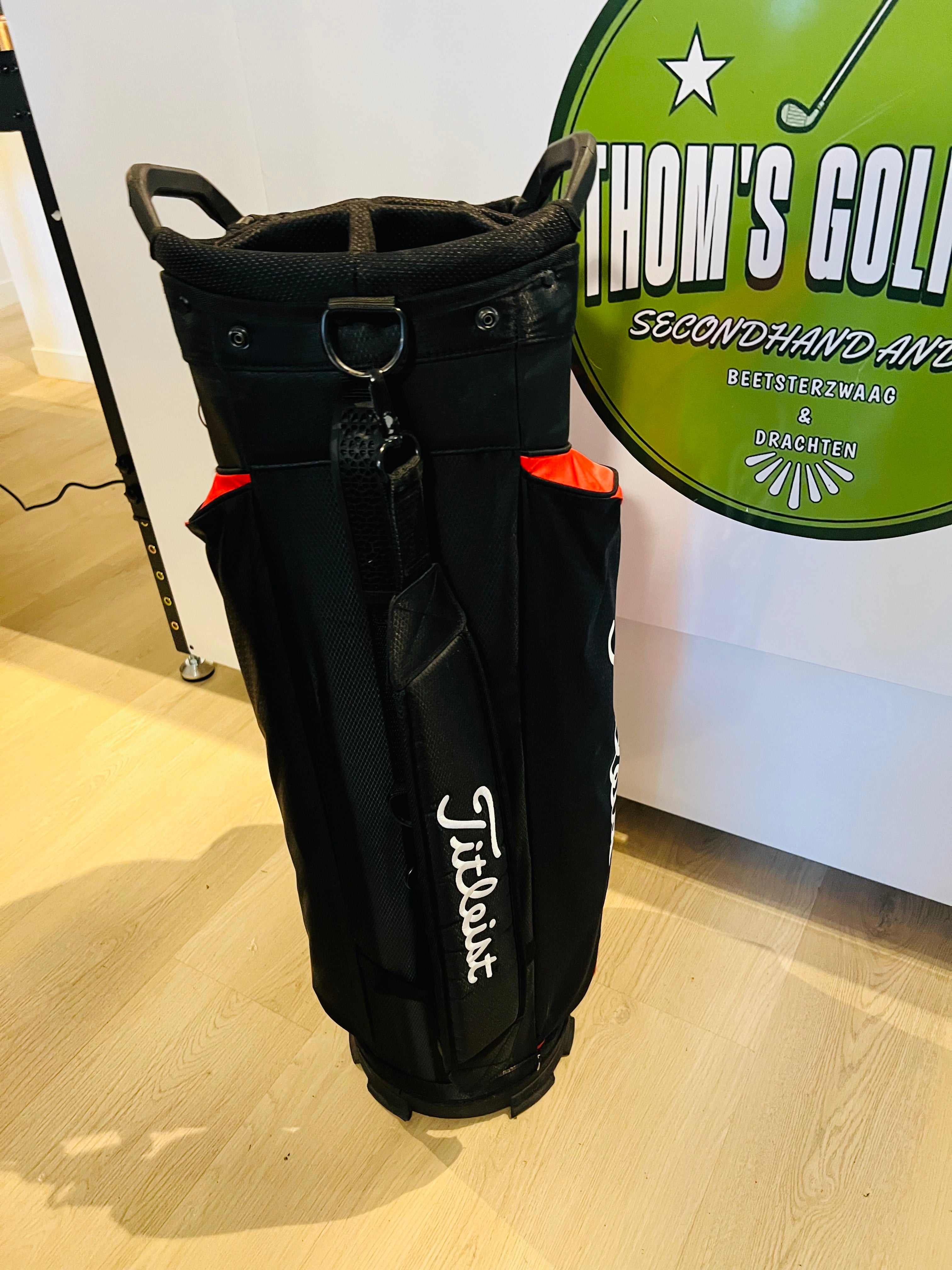 Rode en zwarte Titleist StaDry golfcarttas met meerdere vakken en handvatten, geschikt voor golfers.