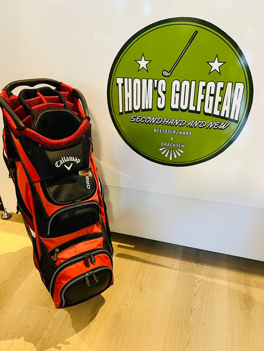 Rode en zwarte Callaway ORG 16 cartbag, golftas met meerdere vakken en handvat, op een golfbaan.