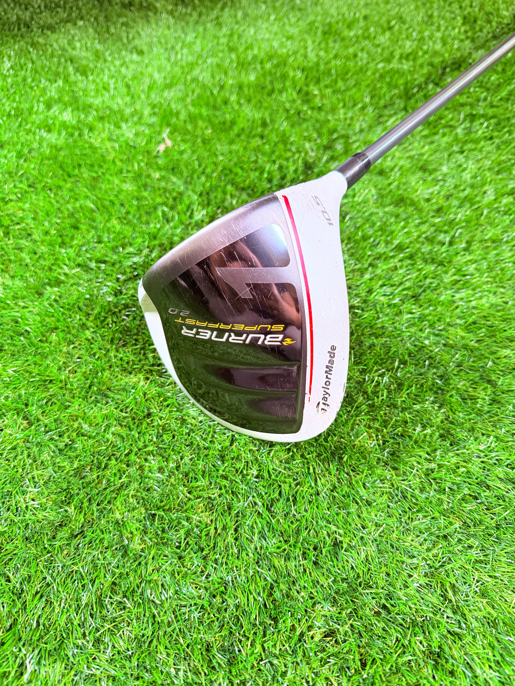 Lichtgewicht TaylorMade Burner SuperFast 2.0 driver met 10,5° rechtshandig, gelegen op een golfbaan met clubs en bal