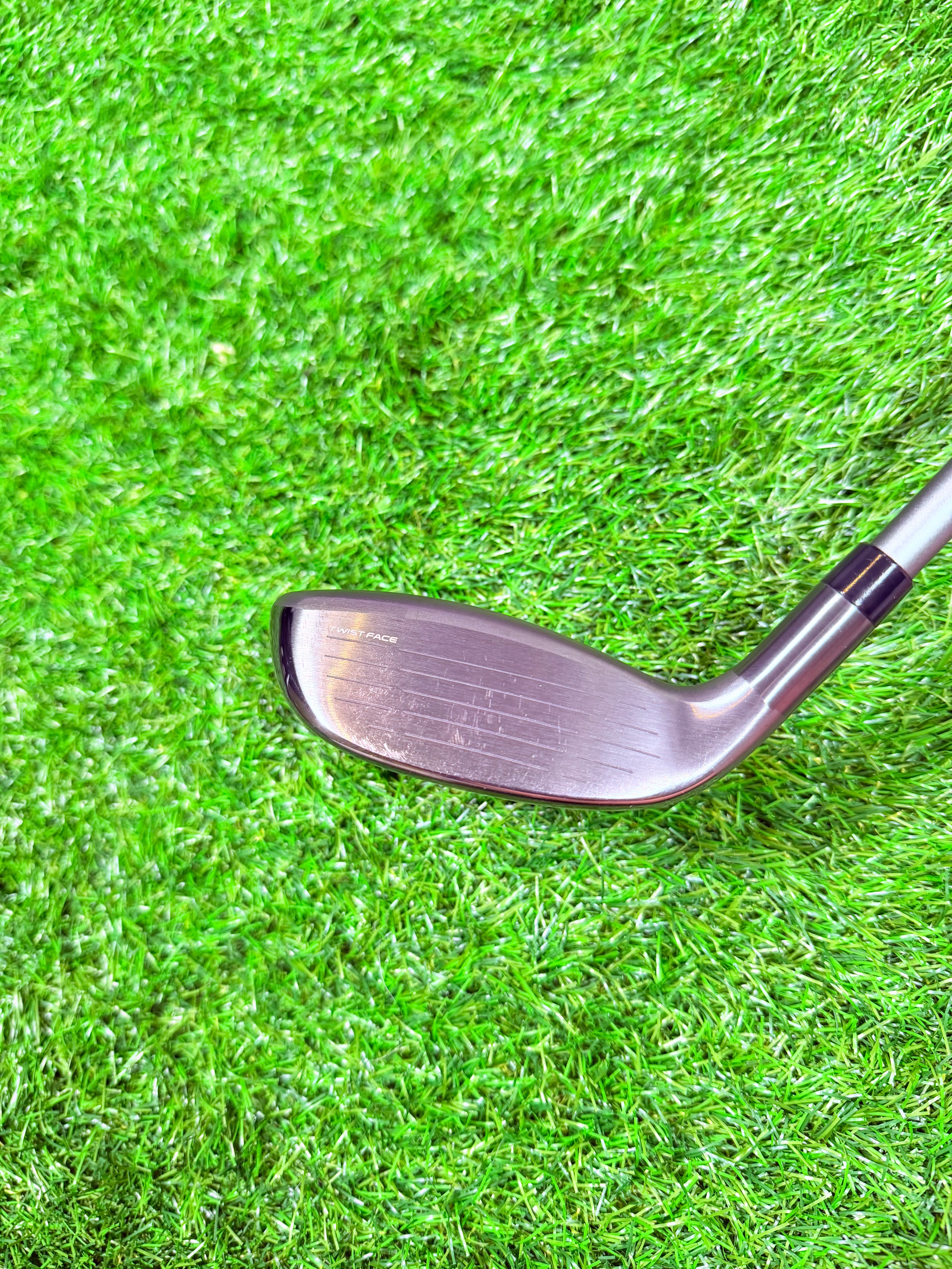 Rechtshandige TaylorMade Qi35 Max hybride 6 (31°) met graphite shaft, ligt op een golfbaan, klaar voor gebruik.