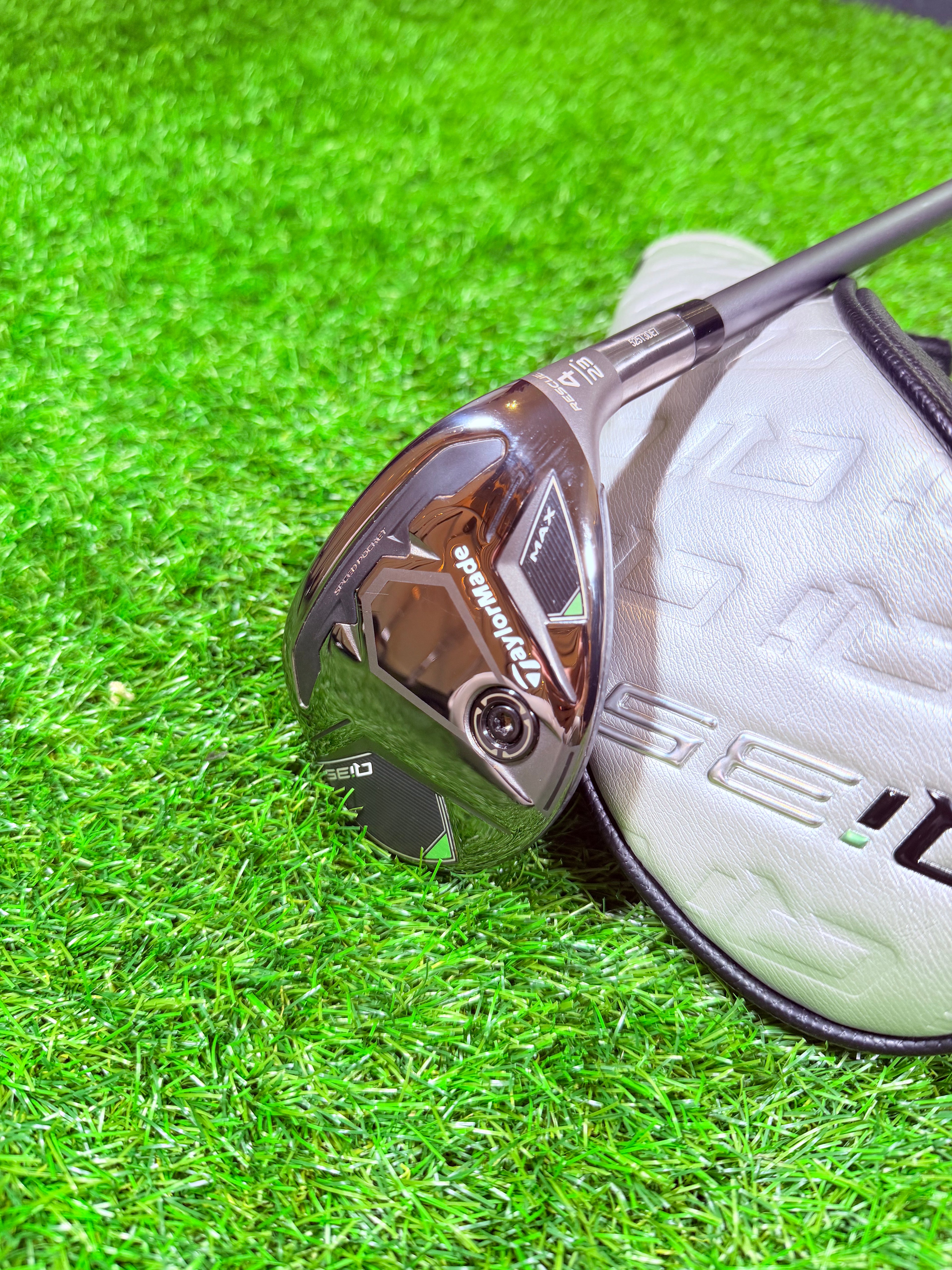 TaylorMade Qi35 Max hybride 4, 23°, rechtshandig, golfclub met blauwe en zwarte details, liggend op gras.