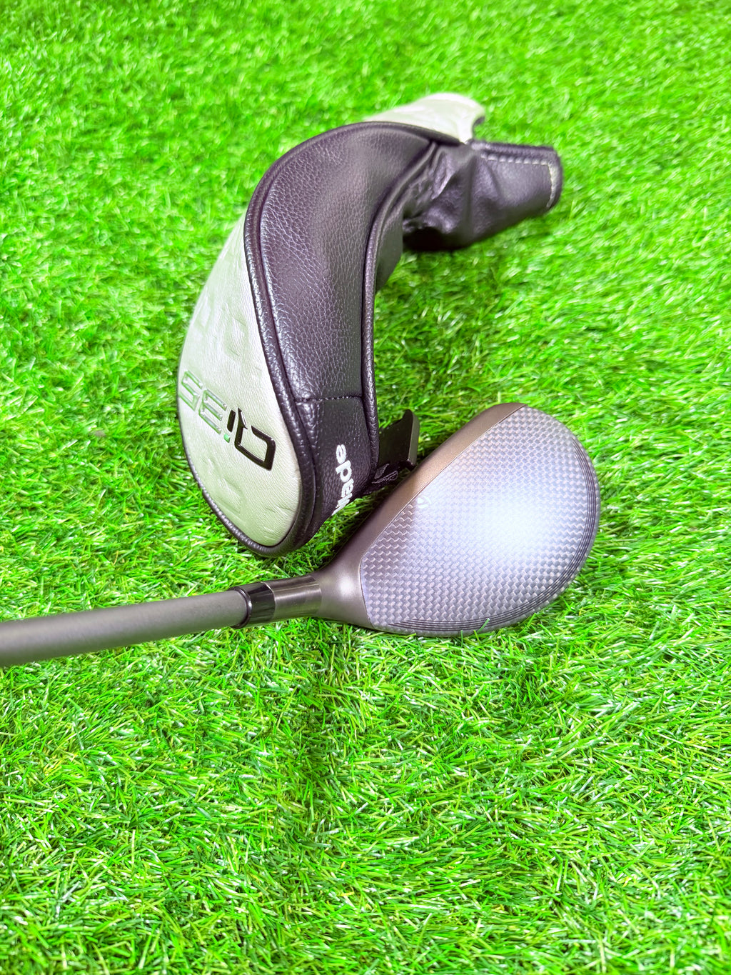 Rechtshandige TaylorMade Qi35 Max Hybride 4, 23°, golfclub met graphite shaft en zwarte grip, op golfbaan.
