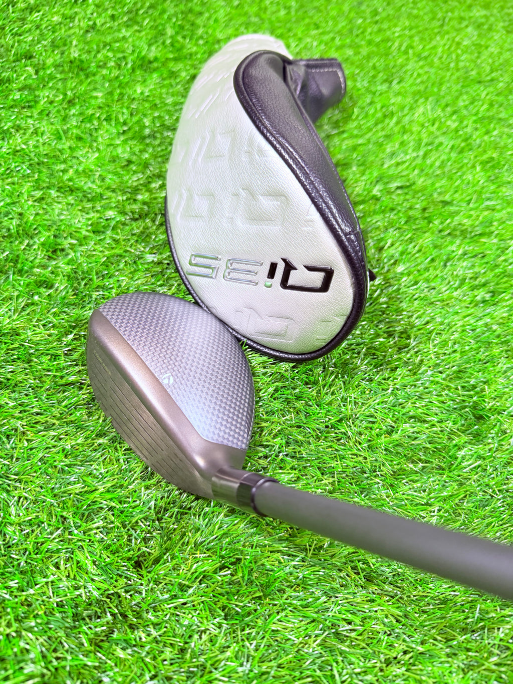 Rechtshandige TaylorMade Qi35 Max hybride 4 met 23° loft, golfclub met blauwe details en graphite shaft, in close-up op golfbaan