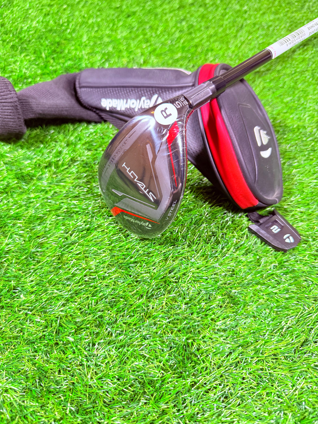 TaylorMade Stealth Hybride 5 (25°) golfclub op een golfbaan, zichtbaar met grip en clubhoofd in close-up.