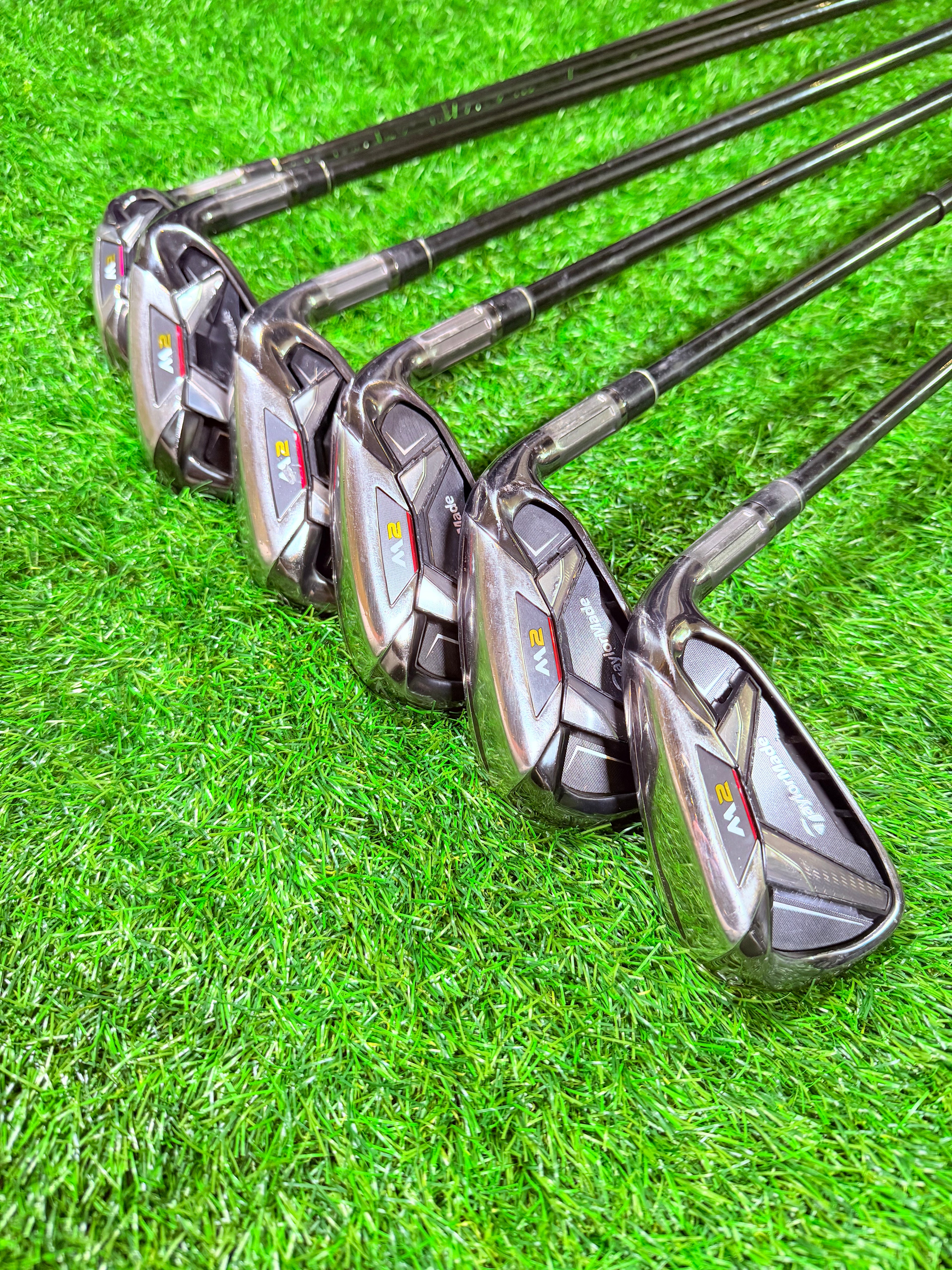 TaylorMade M2 2016 ijzerset 5 t/m PW, rechtshandig, 1 inch verlengd, golfclubs op een golfbaan met golfballen.