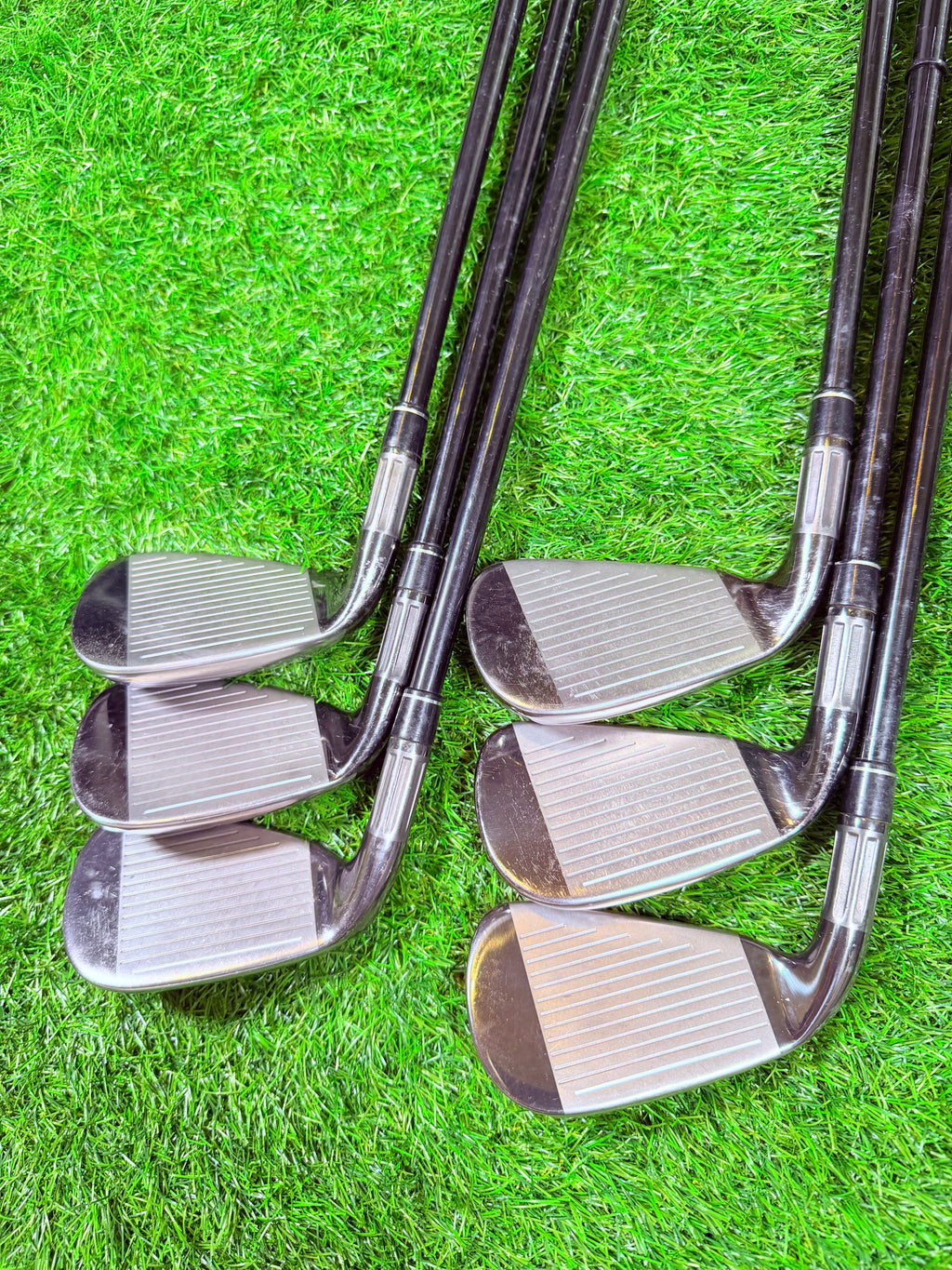 TaylorMade M2 2016 ijzerset 5 t/m PW met +1 inch, rechtshandig, golfclubs met houten handgrepen, liggend op een golfbaan