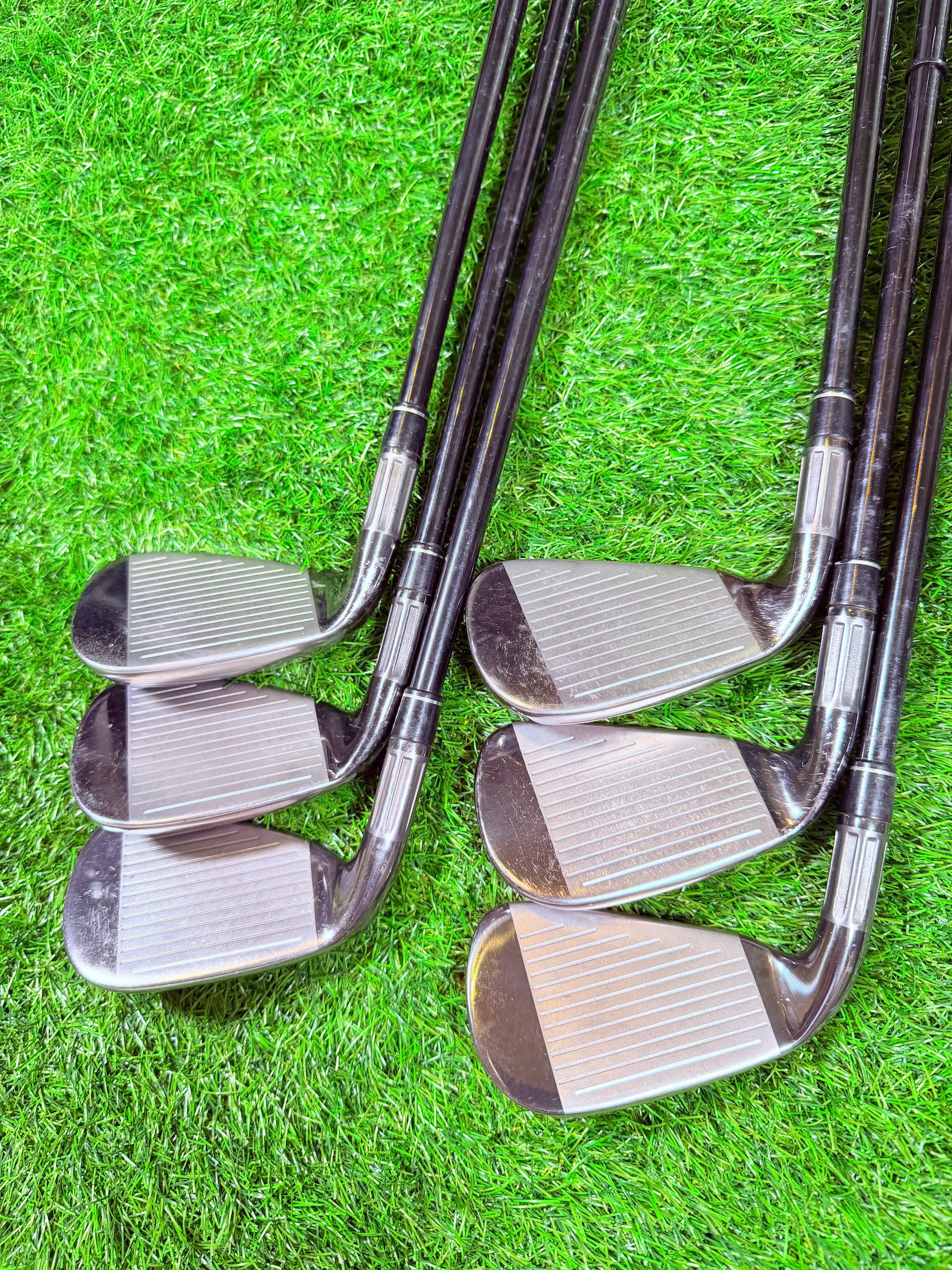 TaylorMade M2 2016 ijzerset 5 t/m PW met +1 inch, rechtshandig, golfclubs met houten handgrepen, liggend op een golfbaan