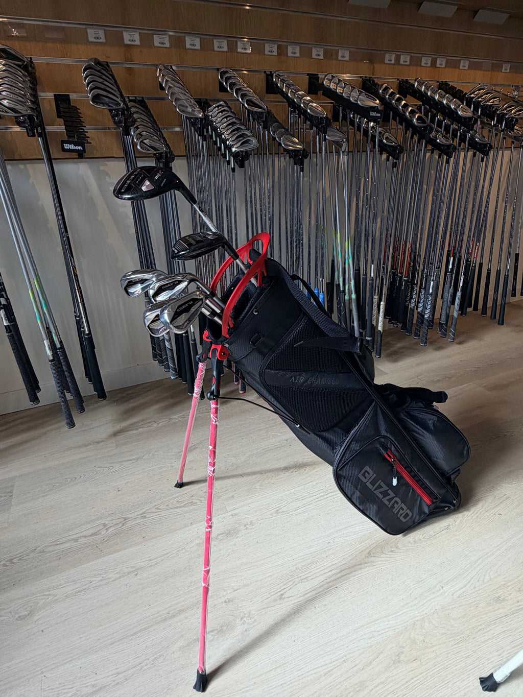 Cobra AIR-X dames golfset met 6 tot PW, hybride 5, 5-wood, putter en standbag, liggend op een golfbaan.