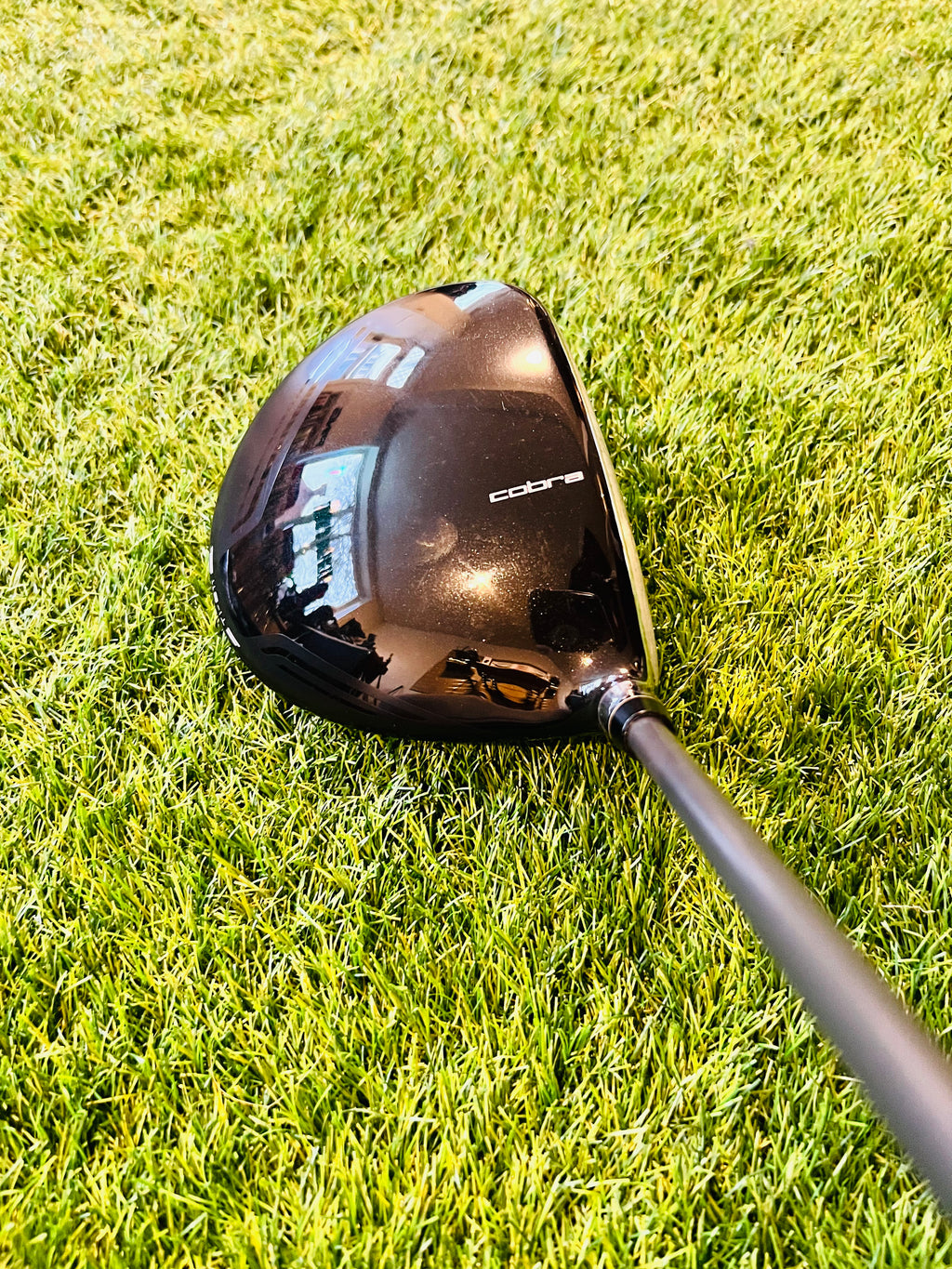 Lijnrechte linkshandige Cobra King F7 Ti driver met 9,5° verstelbare loft, zichtbaar met grip en clubhoofd op golfbaan.